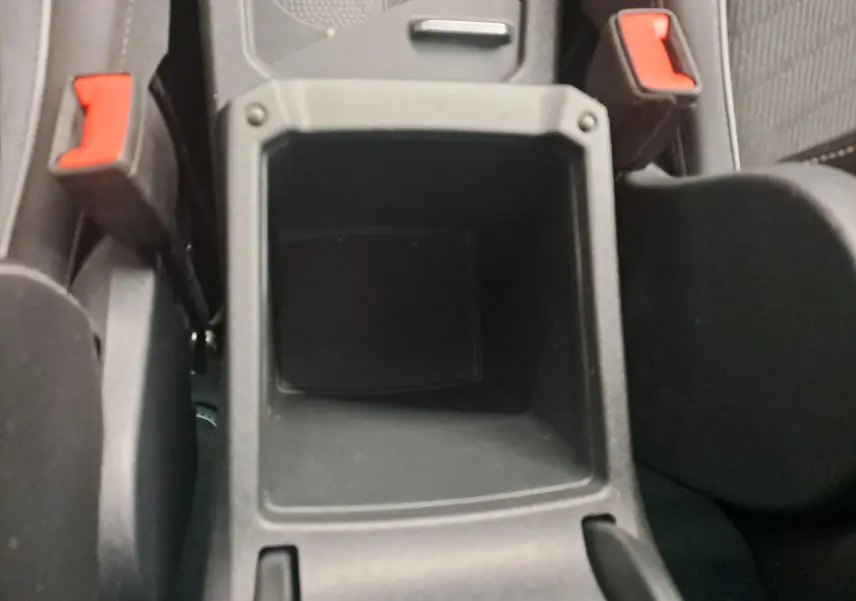 Gros plan sur le rangement central noir entre les sièges avant avec les ceintures rouges du Volkswagen Tiguan 1.4 eHybrid 2023.