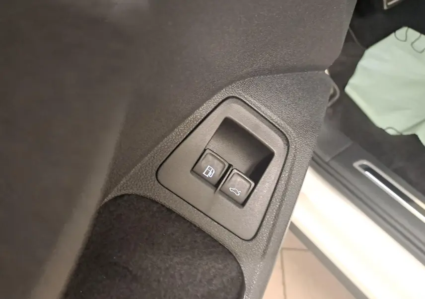 Gros plan sur les boutons d'ouverture de la trappe à carburant et du coffre côté gauche d'un Volkswagen Tiguan blanc pur 2023.
