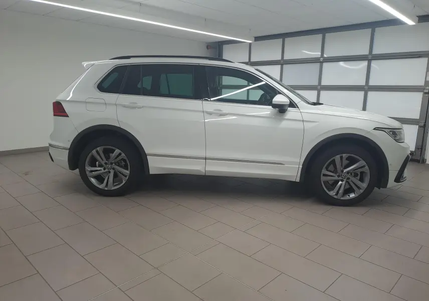 Vue de profil côté gauche d'un Volkswagen Tiguan 1.4 eHybrid blanc pur R-Line 2023 en intérieur.