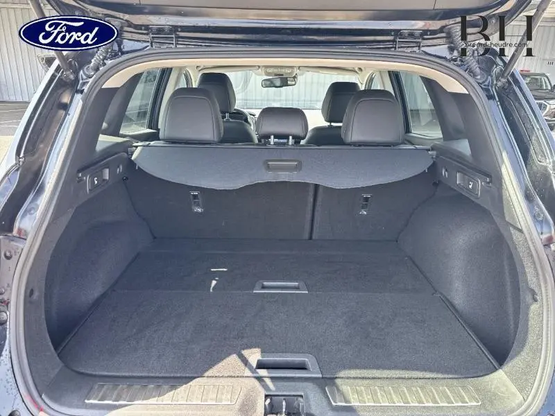 Coffre ouvert vu de l'arrière d'un Renault Kadjar noir étoilé avec banquette arrière et cache-bagages visibles.