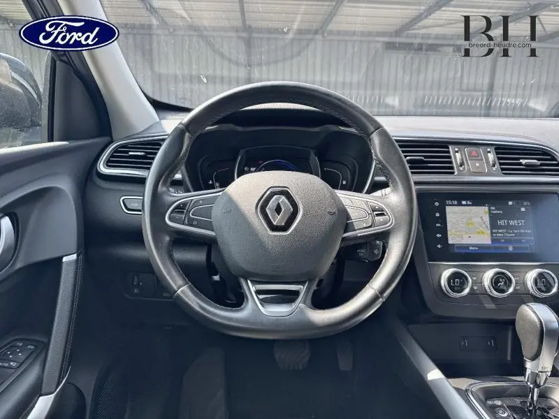 Vue intérieure centrée sur le volant cuir multifonction d'un Renault Kadjar noir étoilé avec écran tactile et levier automatique.