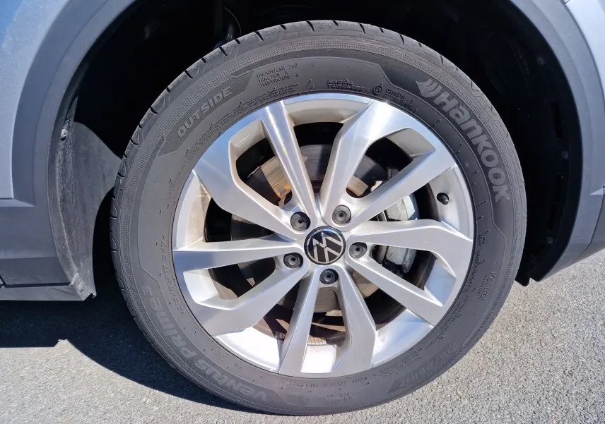 Gros plan sur la roue avant gauche d'un Volkswagen T-Roc gris pyrite avec jante alliage et pneu Hankook.