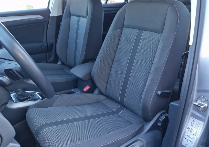 Vue intérieure côté conducteur du Volkswagen T-Roc gris pyrite 2023, mettant en valeur les sièges avant en tissu gris.