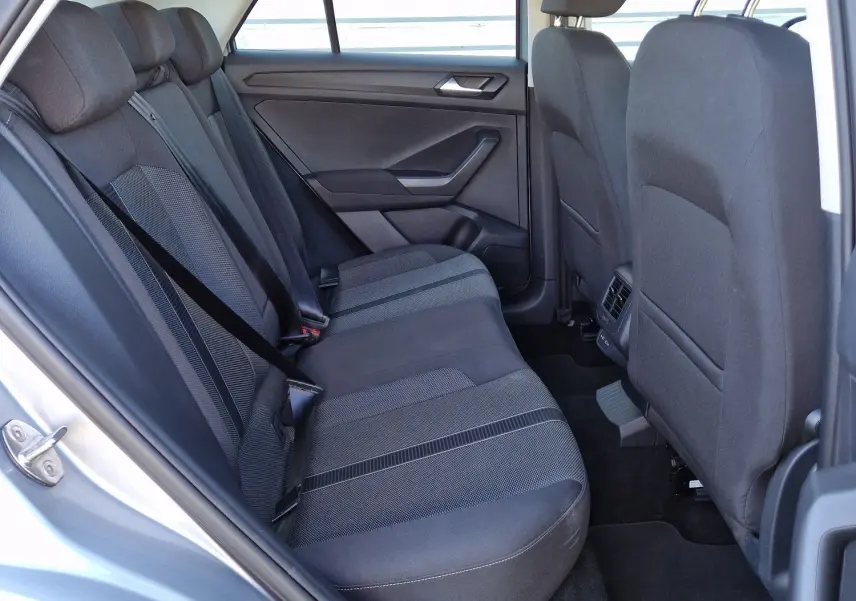 Vue intérieure côté gauche des sièges arrière en tissu gris du Volkswagen T-Roc gris pyrite 2023, avec ceinture de sécurité attachée.