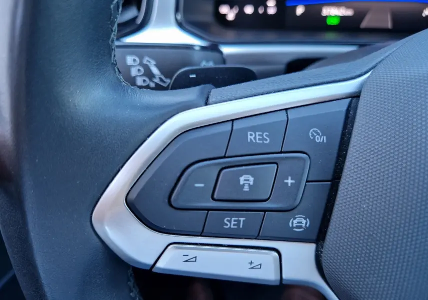 Gros plan sur les commandes du régulateur adaptatif au volant d'un Volkswagen T-Roc gris pyrite 2023.