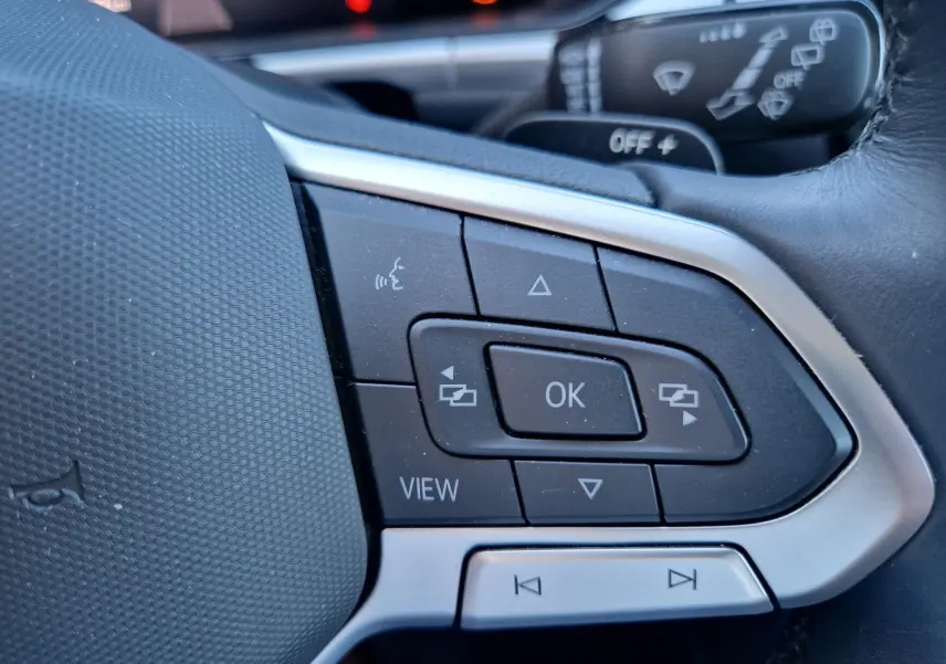 Gros plan sur les commandes multifonctions côté gauche du volant du Volkswagen T-Roc gris Pyrite 2023.