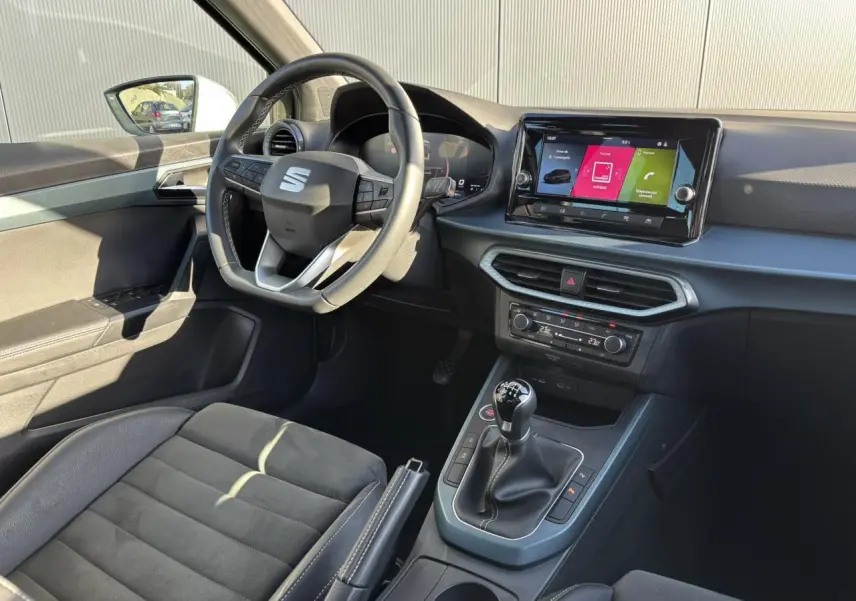 Intérieur avant droit du SEAT Arona TSI 115 Xpérience 2025, volant cuir, écran tactile et sellerie noire.