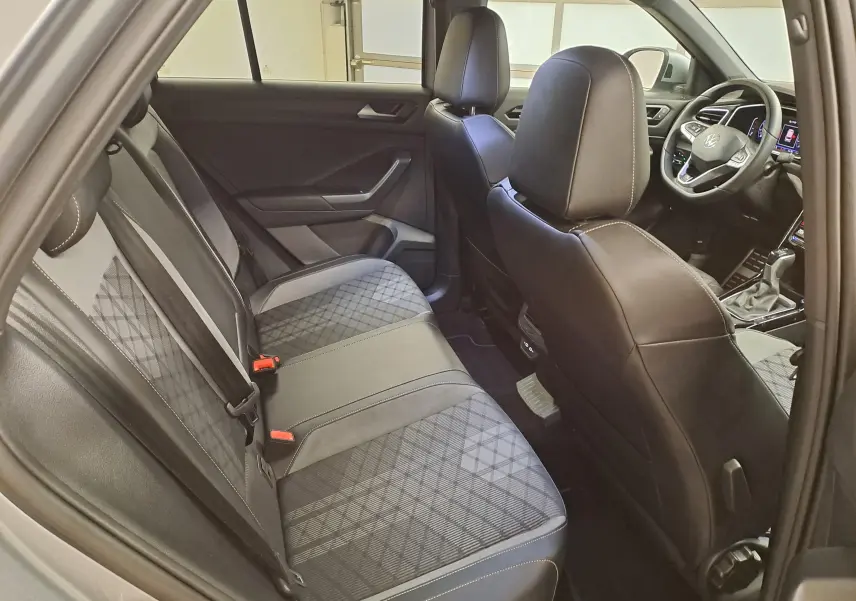 Vue intérieure côté gauche montrant la banquette arrière et les sièges avant en tissu et cuir noir du Volkswagen T-Roc 2025.