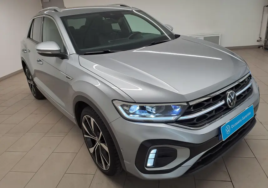 Volkswagen T-Roc gris pyrite en 3/4 avant droit, avec projecteurs Matrix LED allumés et jantes noires 19 pouces.