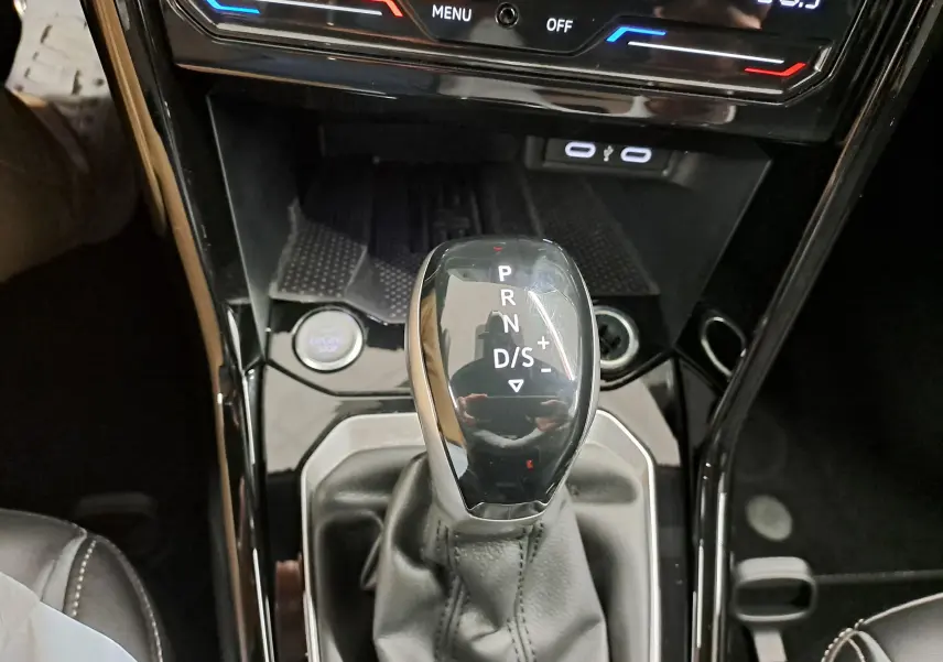 Gros plan sur le levier de vitesses de la boîte auto du Volkswagen T-Roc 1.5 TSI 2025, intérieur noir brillant.
