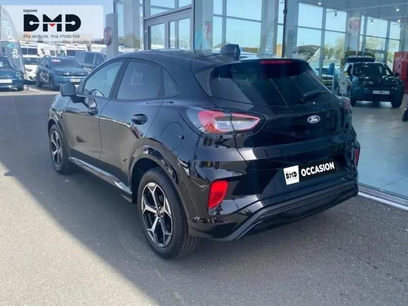 Vue 3/4 arrière droite d'une Ford Puma noire Agate métallisée avec jantes alu et feux arrière LED dans un showroom.
