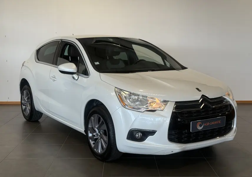 Citroën DS4 blanc vue 3/4 avant droit avec calandre noire et phares allumés en intérieur.