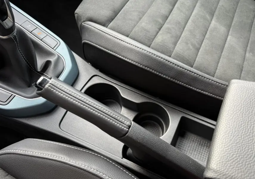 Gros plan sur la console centrale et frein à main cuir du SEAT Arona TSI 115 Xpérience 2025, sièges gris anthracite.
