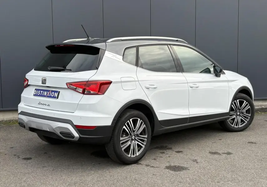 Vue 3/4 arrière droite d'un SEAT Arona blanc Nevada avec toit noir et jantes alliage 17 pouces.