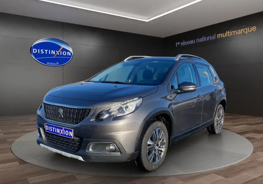 Peugeot 2008 gris platinium en 3/4 avant droit, avec calandre noire et jantes alliage visibles en showroom.