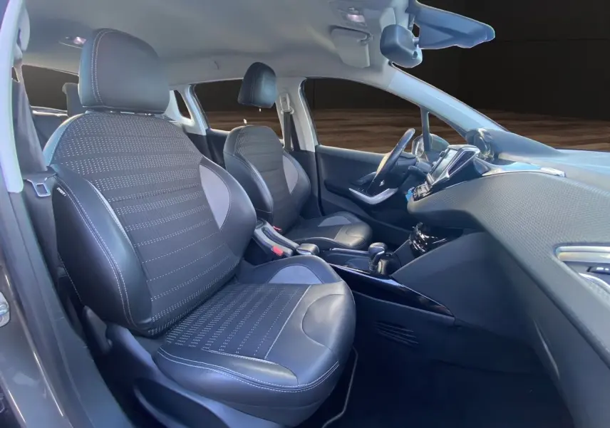 Vue intérieure côté conducteur du Peugeot 2008 gris platinium, mettant en valeur les sièges tissu et cuir avec surpiqûres blanches.