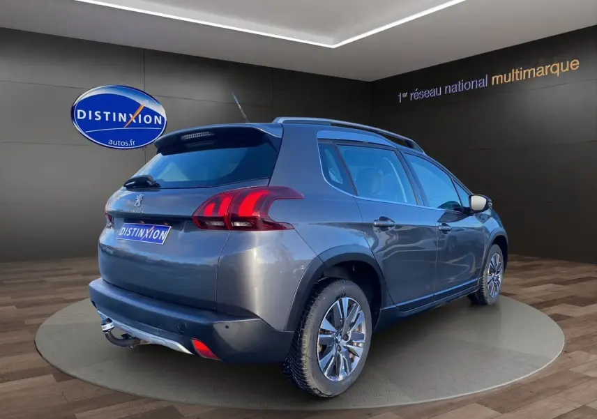 Vue 3/4 arrière droite d’un Peugeot 2008 gris platinium avec feux arrière LED et jantes alliage en showroom.