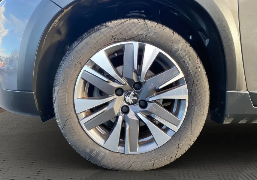 Gros plan sur la roue avant droite d’un Peugeot 2008 gris platinium avec jante alliage distinctive.
