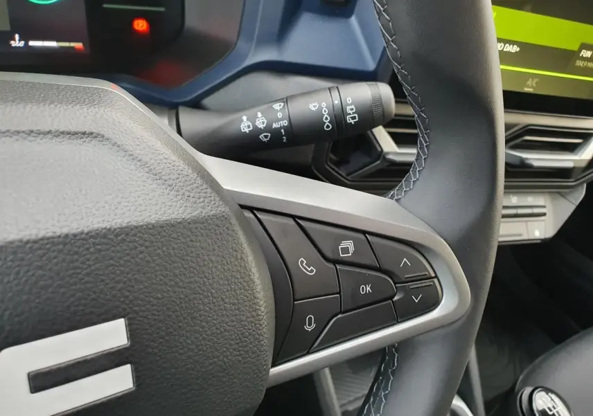 Gros plan sur le volant noir du Dacia Duster 2025, côté droit, avec commandes intégrées et tableau de bord partiellement visible.