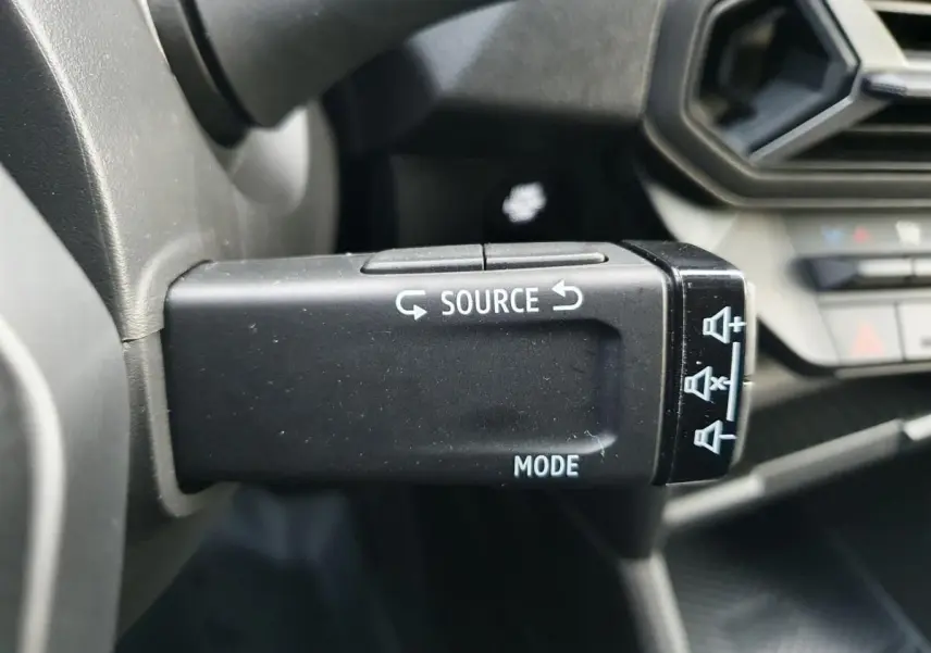 Gros plan sur la commande multimédia noire à gauche du volant du Dacia Duster 2025, intérieur gris et noir.
