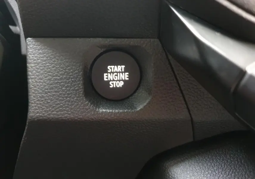 Gros plan sur le bouton Start Engine Stop noir dans l'habitacle du Dacia Duster blanc Glacier 2025.
