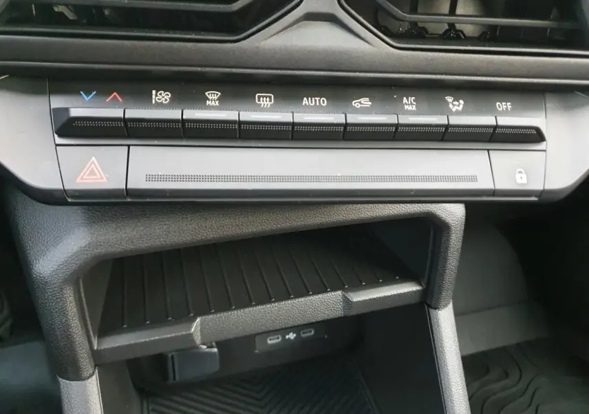 Vue rapprochée de la console centrale du Dacia Duster blanc Glacier 2025, montrant les commandes climatisation et deux prises USB type C.