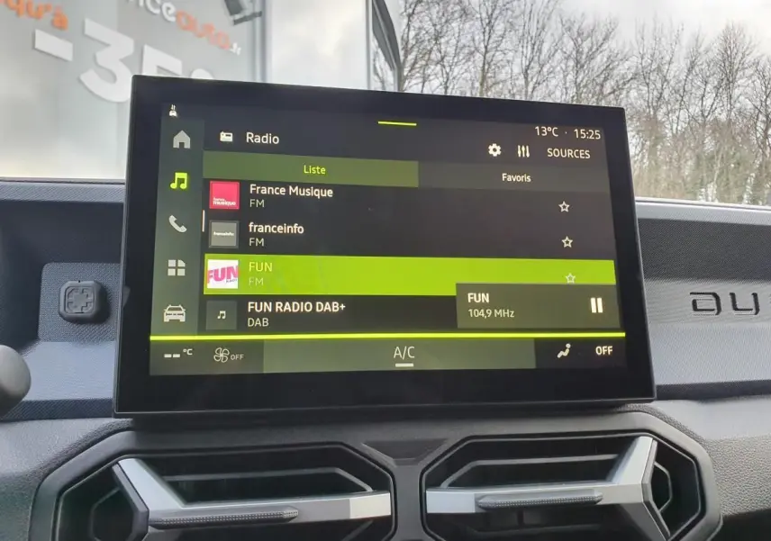Vue intérieure centrée sur l'écran tactile du tableau de bord du Dacia Duster 2025, affichant la radio FM.