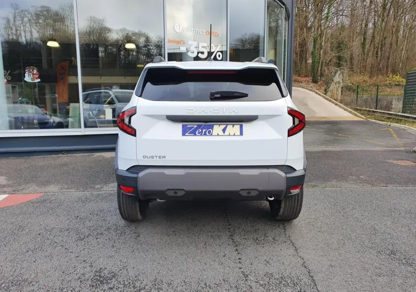Vue arrière d'un Dacia Duster blanc glacier 2025 avec feux arrière en forme de C et pare-chocs gris foncé.