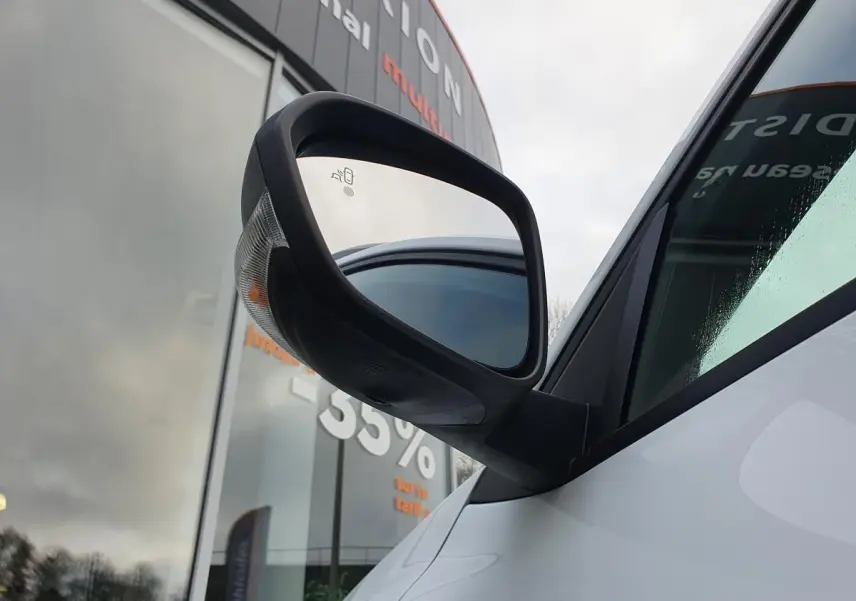 Gros plan sur le rétroviseur droit noir du Dacia Duster blanc glacier, avec vitre teintée en arrière-plan.