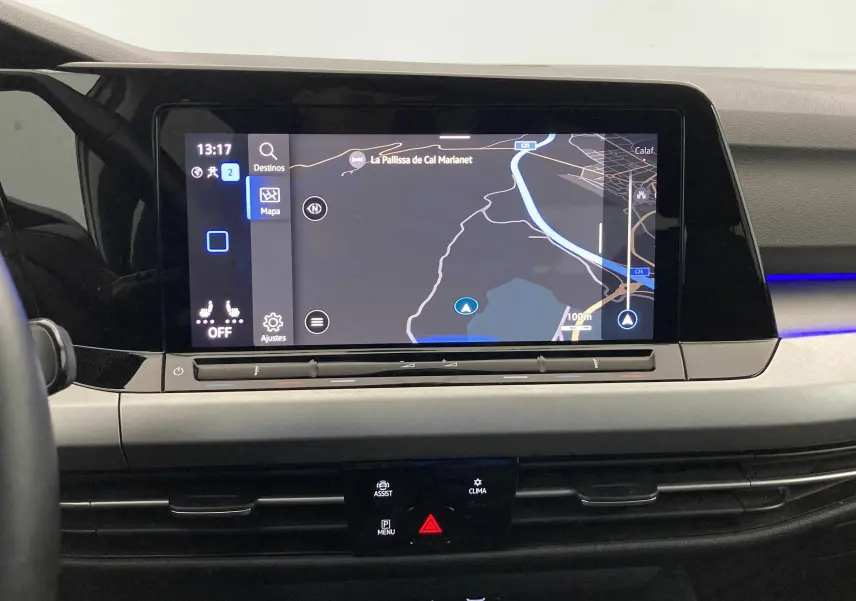 Vue intérieure du tableau de bord de la Volkswagen Golf VIII gris reflex avec écran tactile GPS et éclairage d'ambiance bleu.