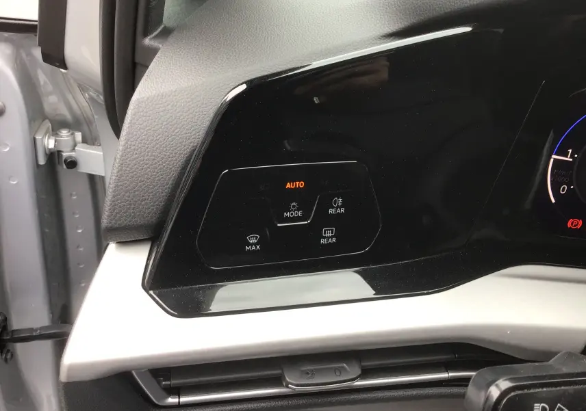 Détail du tableau de bord côté gauche d'une Volkswagen Golf VIII gris reflex, avec commandes d'éclairage et désembuage.