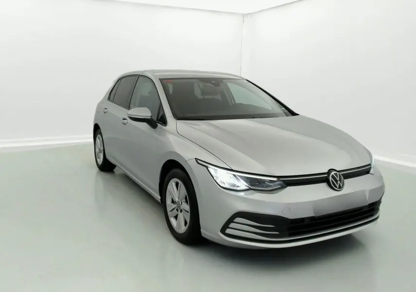 Volkswagen Golf VIII gris reflex vue 3/4 avant droit dans un studio lumineux, phares allumés.