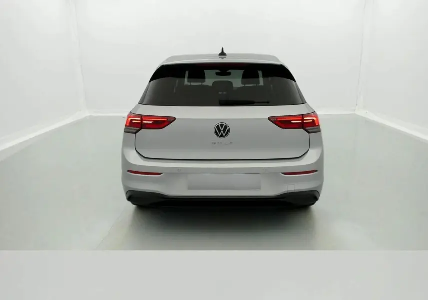Vue arrière d'une Volkswagen Golf VIII gris reflex avec feux arrière allumés dans un studio blanc.