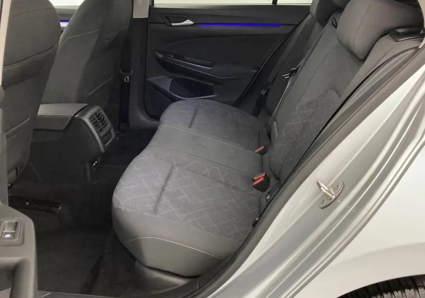 Vue intérieure côté droit sur la banquette arrière grise avec éclairage d'ambiance bleu d'une Volkswagen Golf VIII 2020.