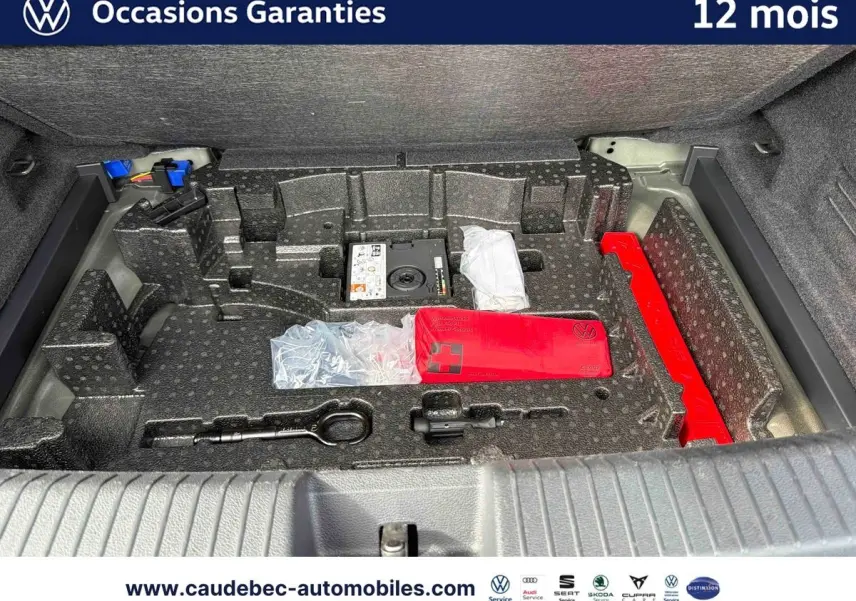 Coffre ouvert du Volkswagen T-Roc Cabriolet noir montrant le rangement avec kit de secours et outils intégrés.