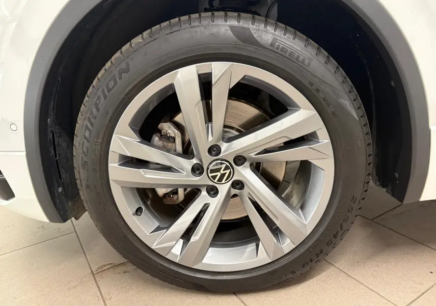 Gros plan sur la roue avant gauche du Volkswagen Tiguan blanc pur 2023 avec jante alliage R-Line distinctive.