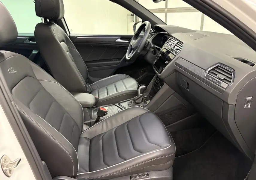 Intérieur noir du Volkswagen Tiguan 2023 vu côté passager, avec sièges en cuir R-Line et tableau de bord moderne.