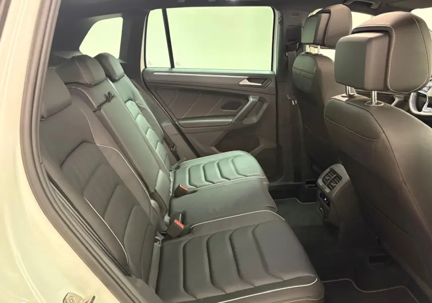 Vue intérieure côté gauche des sièges arrière en cuir noir avec surpiqûres blanches du Volkswagen Tiguan 1.4 eHybrid 2023 blanc pur R-Line Exclusive.