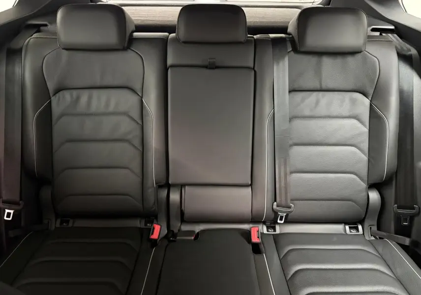Vue intérieure des sièges arrière en cuir noir du Volkswagen Tiguan 1.4 eHybrid 2023, avec appuie-têtes et ceintures visibles.