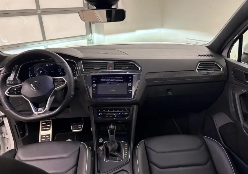 Vue intérieure du Volkswagen Tiguan 1.4 eHybrid 2023, tableau de bord et console centrale noirs avec finition R-Line exclusive.