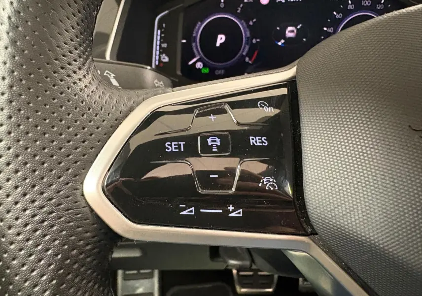 Gros plan sur les commandes de régulateur de vitesse au volant perforé du Volkswagen Tiguan blanc pur 2023 hybride rechargeable.