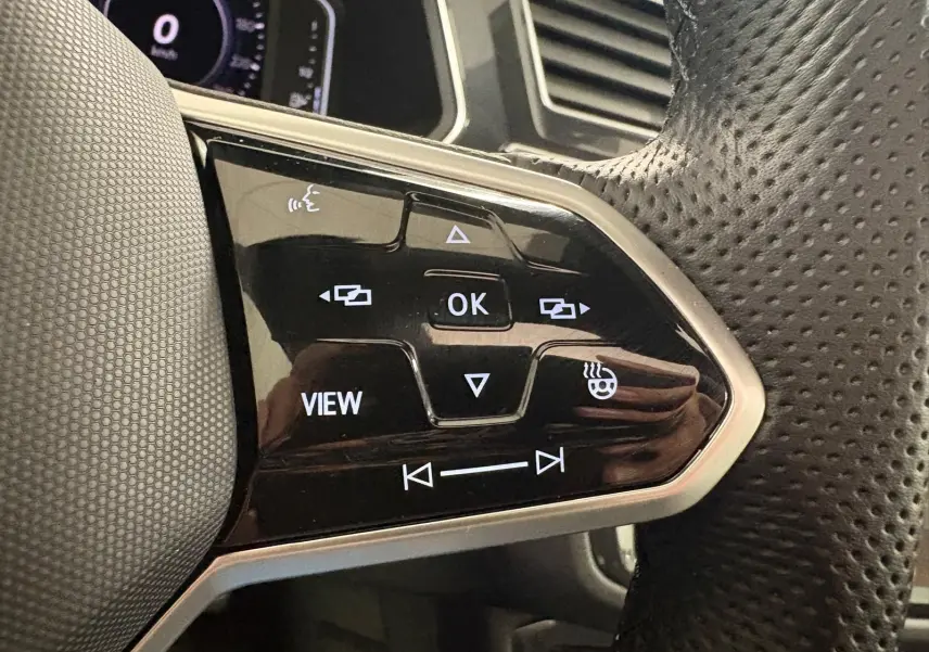 Gros plan sur les commandes multifonctions du volant en cuir perforé du Volkswagen Tiguan 1.4 eHybrid blanc pur 2023.