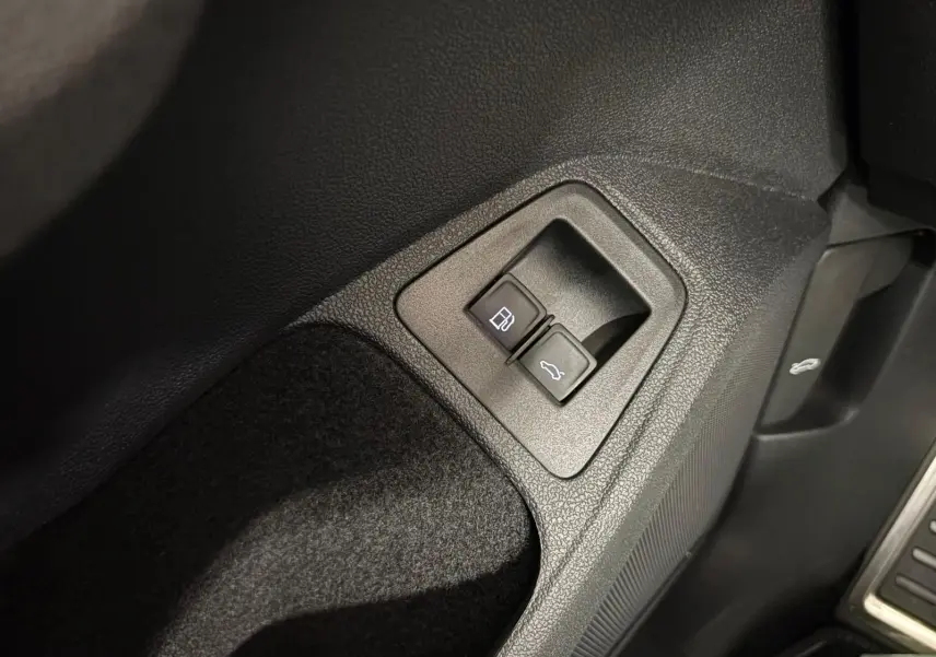Boutons d'ouverture du réservoir et du coffre sur le côté gauche intérieur du Volkswagen Tiguan blanc 2023 R-Line Exclusive.