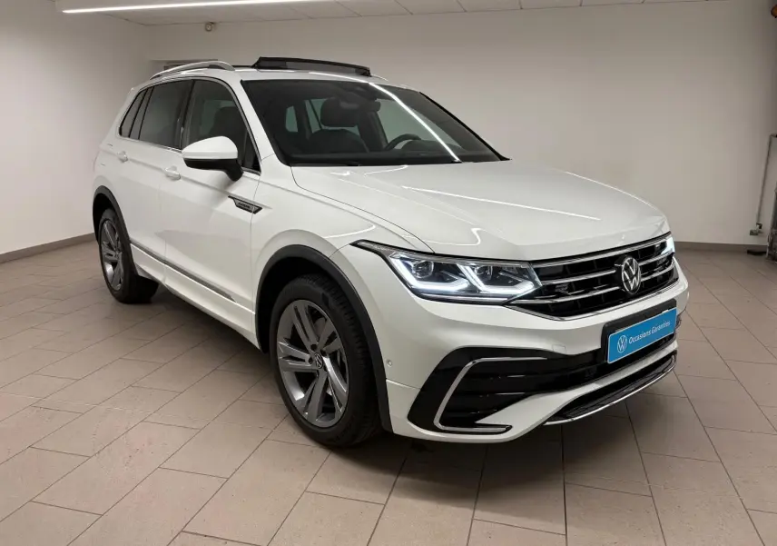 Volkswagen Tiguan 1.4 eHybrid blanc pur en vue 3/4 avant droit, avec finition R-Line Exclusive et phares LED allumés.