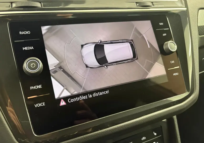 Vue aérienne du Volkswagen Tiguan blanc pur 2023 affichée sur l'écran central avec avertissement de distance.