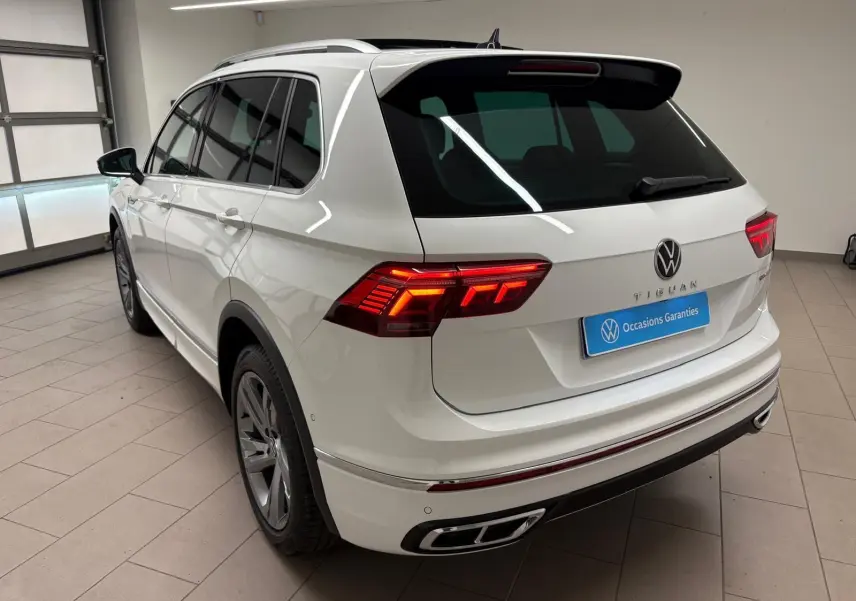 Vue 3/4 arrière gauche d'un Volkswagen Tiguan blanc pur 2023 avec feux LED et finition R-Line Exclusive.