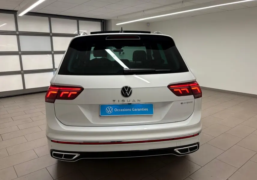 Vue arrière d'un Volkswagen Tiguan blanc pur 2023 hybride rechargeable avec feux LED et double sortie d'échappement intégrée.