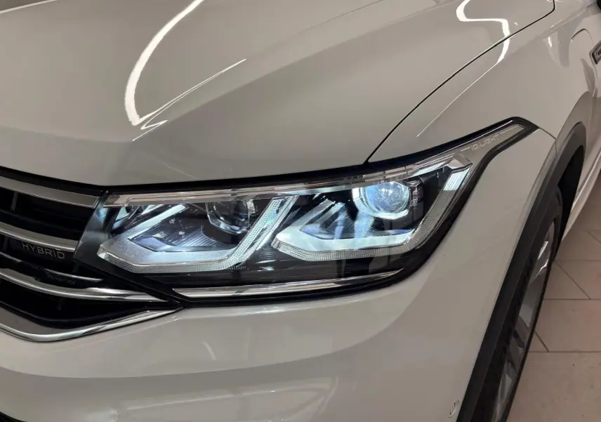 Gros plan sur le phare avant droit allumé du Volkswagen Tiguan blanc pur 1.4 eHybrid R-Line Exclusive 2023.
