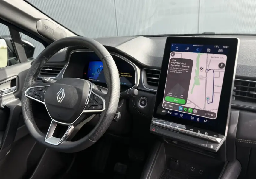 Vue intérieure du tableau de bord et volant Renault Symbioz E-Tech, écran tactile GPS vertical et commandes au volant visibles.