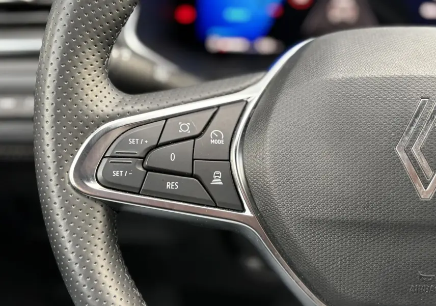 Gros plan sur les commandes gauche du volant perforé gris du Renault Symbioz E-Tech Full Hybrid 2025.